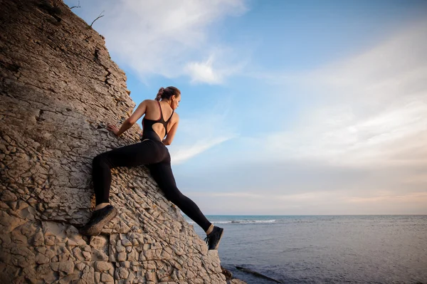 Kvinnliga rock klättrare solnedgången över havet — Stockfoto