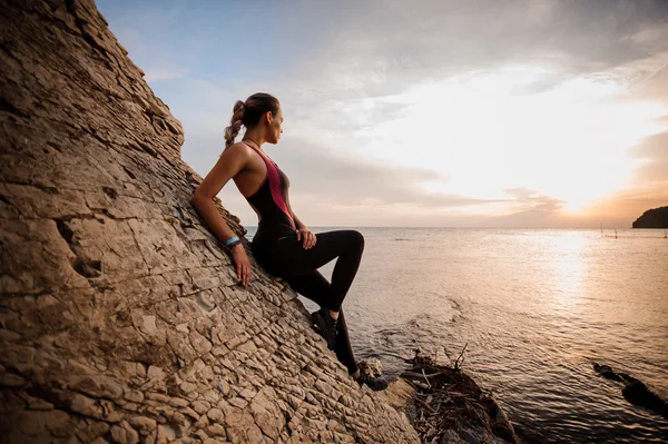 Kvinnliga rock klättrare solnedgången över havet — Stockfoto
