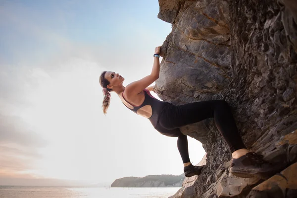 Unga kvinnliga rock klättrare klättrar utmanande rutt på överhängande klippa — Stockfoto