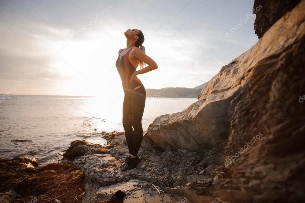 Female rock climber watching sunset over sea