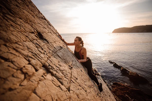 Жіночий екстремальний альпініст завоював круту скелю проти заходу сонця над річкою . — стокове фото