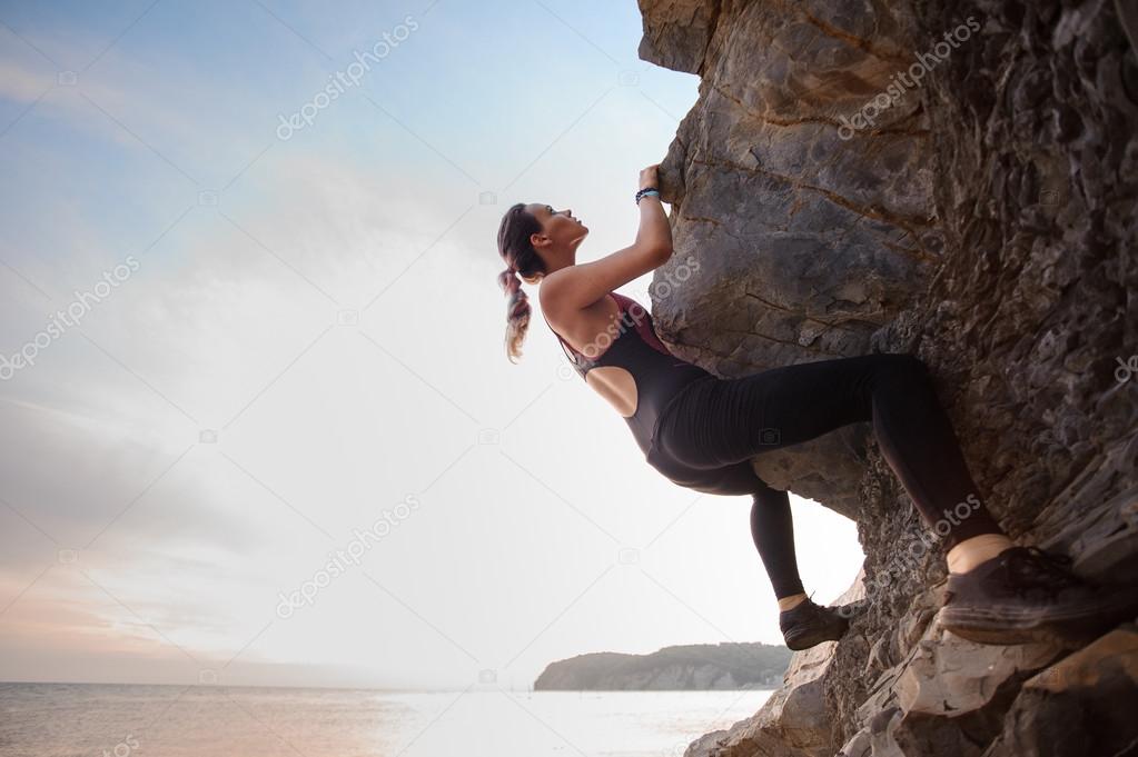 Young female rock climber climbing challenging route on overhanging