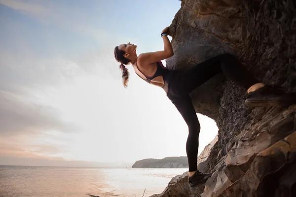 Jonge vrouwelijke rock klimmer uitdagende route klimmen op overhangende klip — Stockfoto