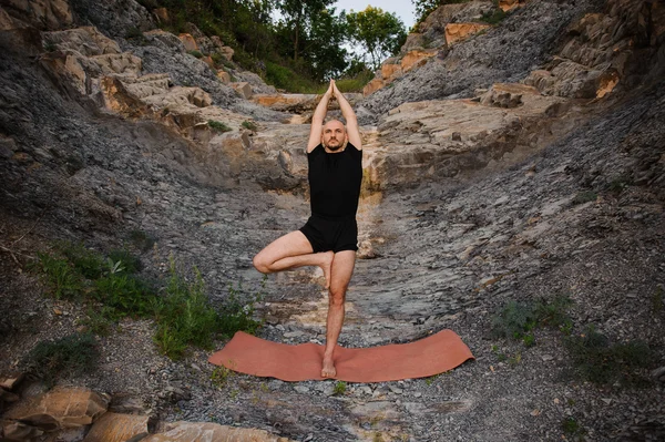 Atletische Man doet Yoga op de rotsen — Stockfoto