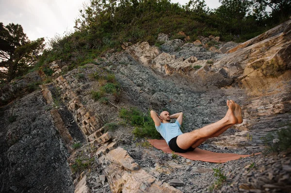 Gezonde man doen yoga achterover te leunen op de rotsen — Stockfoto