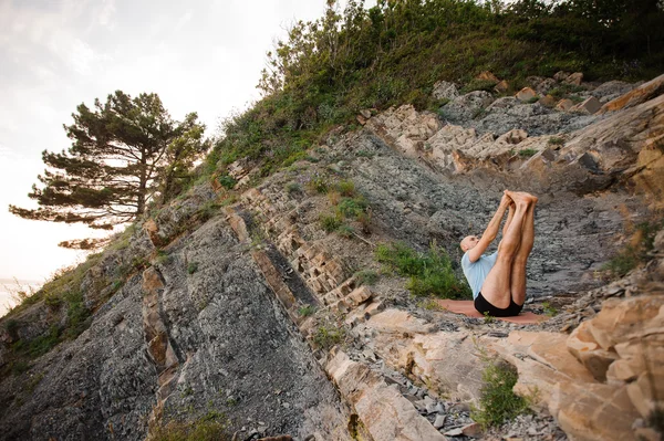 Gezonde man doen yoga achterover te leunen op de rotsen — Stockfoto