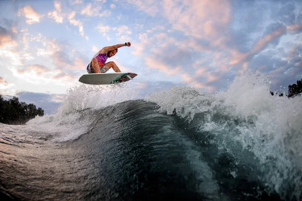 Chico salta enérgicamente por encima de la ola en el wakeboard estilo surf. Tiempo libre de verano —  Fotos de Stock