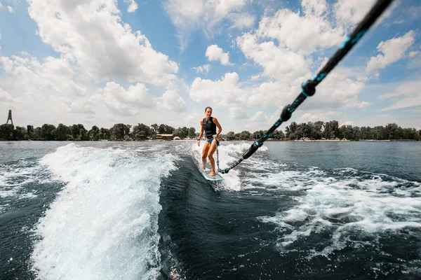 Utsikt över kvinnan som håller rep och rider på wake board på våg — Stockfoto
