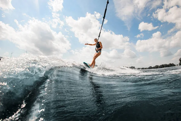 Активна молода жінка їде на серфінгу, тримаючи мотузку моторного човна — стокове фото