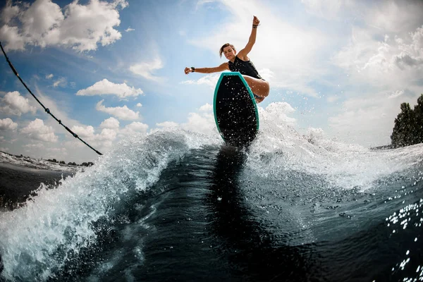 Jeune femme sportive sautant sur la planche sur la vague de la rivière — Photo