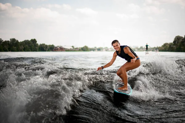 Ενεργός χαρούμενη γυναίκα ιππασία στο wake surf στα γόνατα κάμψης — Φωτογραφία Αρχείου