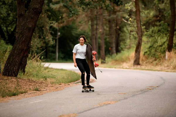 Atraktivní žena jezdí na skateboardu s wakeboard v ruce — Stock fotografie