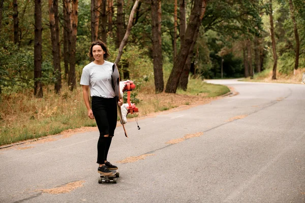 Mulher sorrindo passeios de skate com wakeboard no dia de verão — Fotografia de Stock
