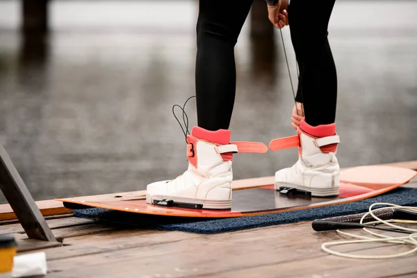 Close-up rear view on athletic female legs fixed in boots of wakeboarding board
