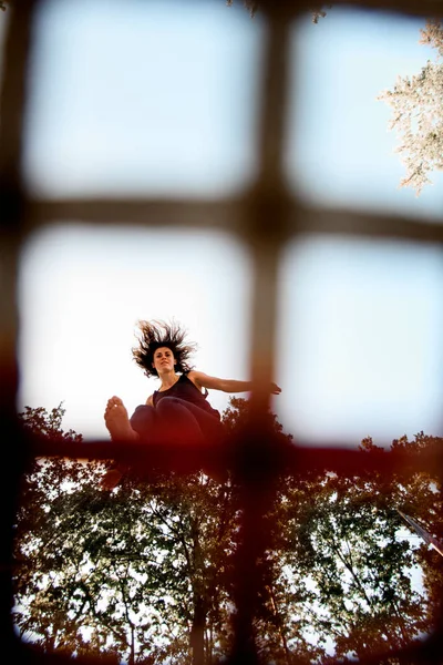 Utsikt genom nätet av vacker kvinna hoppar på studsmatta — Stockfoto