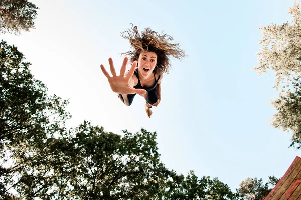 Verrast vrouw met springen hoog in de lucht en kijken naar de camera — Stockfoto