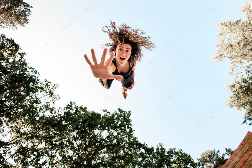 surprised woman with jumping high in the air and looking at the camera