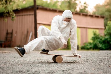 Kapüşonlu beyaz giysili adam teknede dengede duruyor..
