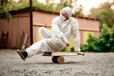 Kapüşonlu beyaz koruyucu giysili kişi gemide dengede duruyor..