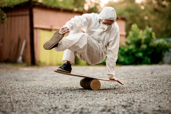 Hombre en traje protector blanco realiza truco en el tablero de equilibrio —  Fotos de Stock