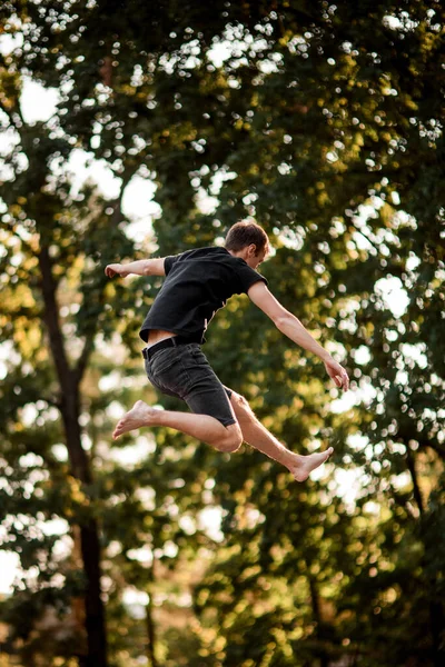 Uitzicht op de mens springen in de lucht tegen de achtergrond van groene bomen — Stockfoto