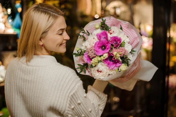 Όμορφη ξανθιά γυναίκα που κρατάει ένα μπουκέτο φρέσκα ανοιξιάτικα λουλούδια στα χέρια της. — Φωτογραφία Αρχείου