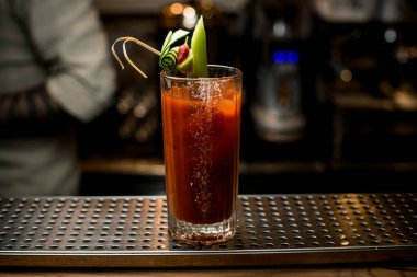 Barda duran yeşil salatalıkla süslenmiş bir bardak içki.