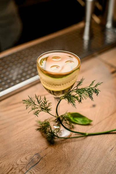 Verre avec boisson et tranche de concombre debout sur la surface en bois du bar — Photo