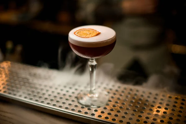 Vista sul bicchiere di vino di bevanda con schiuma e fetta di agrumi si trova sul bancone del bar. — Foto Stock