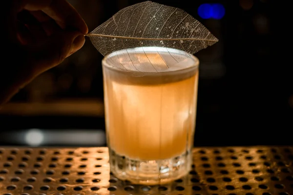 Nahaufnahme eines altmodischen Getränkeglases mit Schaumstoff, der mit Blatt auf der Theke dekoriert ist — Stockfoto