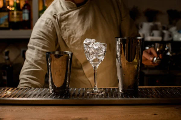 얼음과 샤커 컵이 가득 들어 있는 투명 한 와인 잔이바 카운터에 서 있다. — 스톡 사진