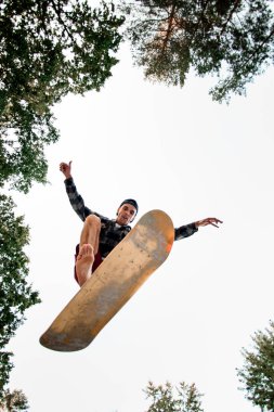 Kaykay simülatörlü sporcu gökyüzünün arka planına doğru yükseliyor