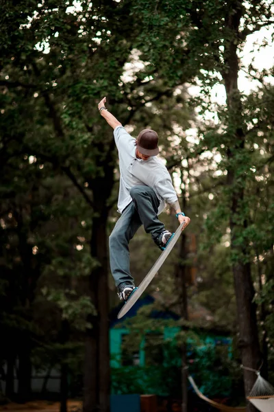 Hombre activo con simulador de skate salta magistralmente en el trampolín —  Fotos de Stock