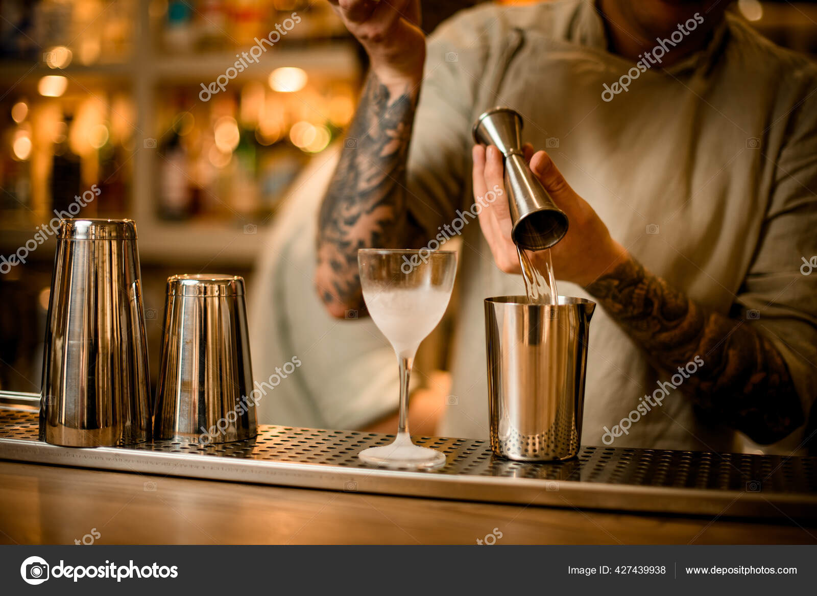 View on bar counter behind which bartender pours liquid from jigger into measuring  cup. Stock Photo by ©Fesenko 427439938