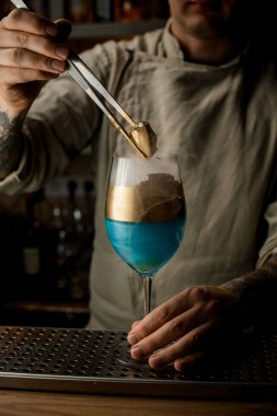 Erkek barmen altın rengi buzu nazikçe buharlı şarap kadehinin üzerinde tutuyor.