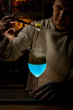 Barmen, bardağın üstünde altın bir buz parçası tutuyor ve şuna bak.