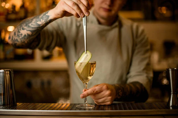 Blick auf Barmann dekoriert Cocktailglas mit Gurkenscheibe mit Pinzette — Stockfoto