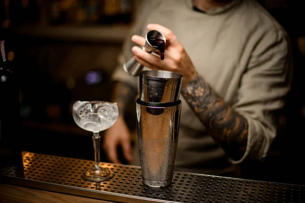 Hombre en el bar magistralmente vierte bebida de metal jigger en agitador — Foto de Stock