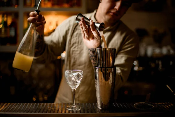 Vista en barman vierte bebida de metal jigger en agitador en barra mostrador — Foto de Stock