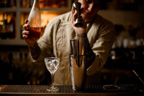 Barman magistralmente vierte bebida de jigger de metal en agitador en barra de bar — Foto de Stock