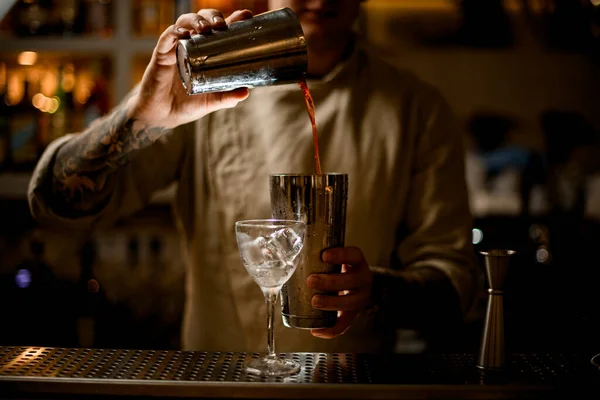 Cantinero vertiendo cóctel de una copa en otra copa. — Foto de Stock