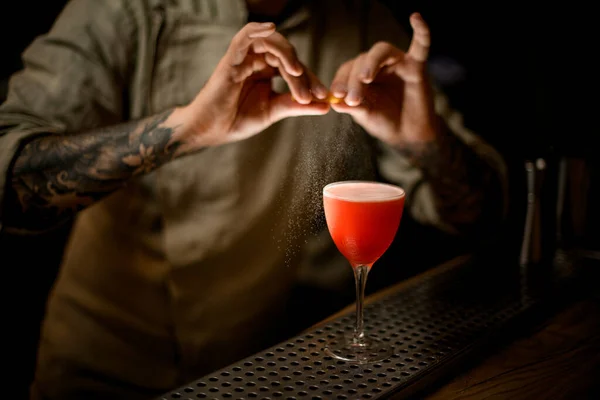 Barman κρατά απαλά φλούδα λεμονιού και ψεκάζει στο γυαλί με φωτεινό κοκτέιλ. — Φωτογραφία Αρχείου