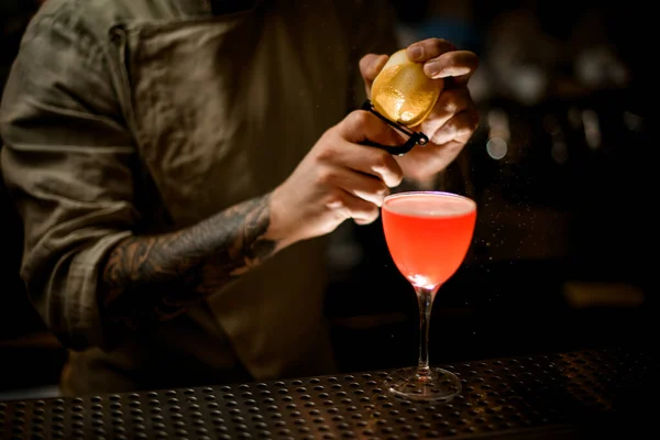 Man i baren håller citron i händerna och skär av skalet med kniv — Stockfoto