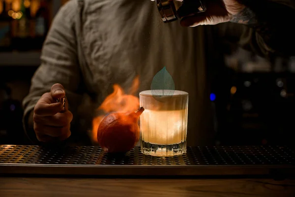 Camarero salpica y prende fuego a la calabaza en el bar. Vaso de bebida con espuma cerca — Foto de Stock