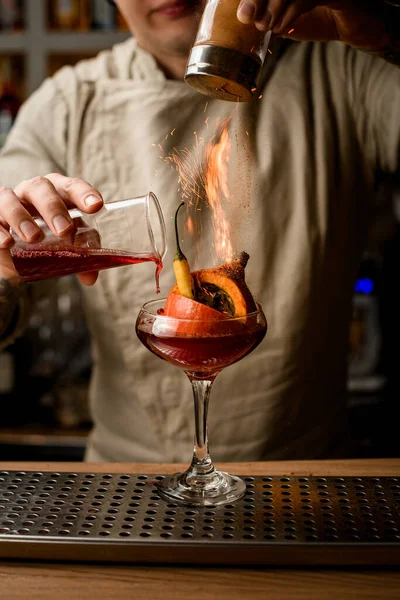 Uomo barista aggiungere ingredienti al vetro con zucca e pepe all'interno e fa fuoco su di esso — Foto Stock
