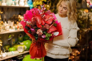 Farklı çiçeklerden yapılmış harika kırmızı buket. Kadının ellerinde ambalaj kağıdı ile süslenmiş.