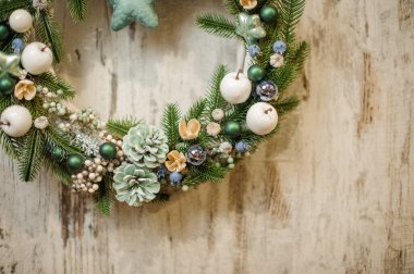 Yeşil ladin dalları, çam kozalakları, böğürtlen ve oyuncaklarla süslenmiş Noel çelengi manzarası.