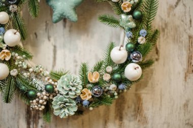 Yeşil ladin dalları, çam kozalakları, böğürtlen ve oyuncaklarla süslenmiş Noel çelengi..