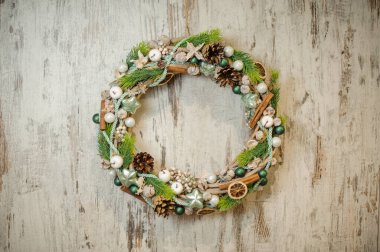 Yeşil ladin dalları, çam kozalakları, beyaz böğürtlen ve tarçın çubuklarıyla süslenmiş zarif Noel çelengi..