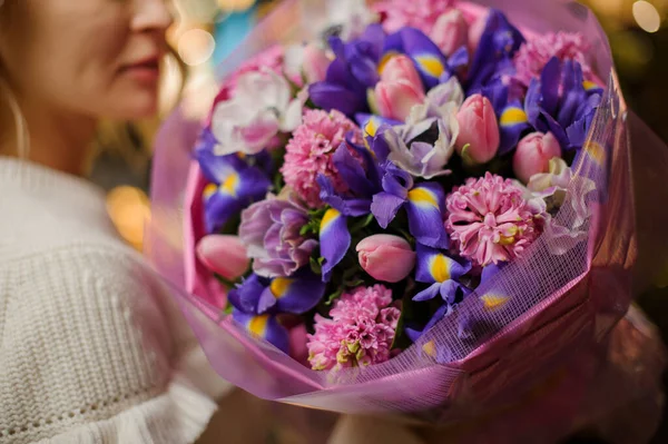 Крупним планом букет з квітами ірисів, рожевими гіацинтами і тюльпанами, загорнуті в декоративний папір — стокове фото